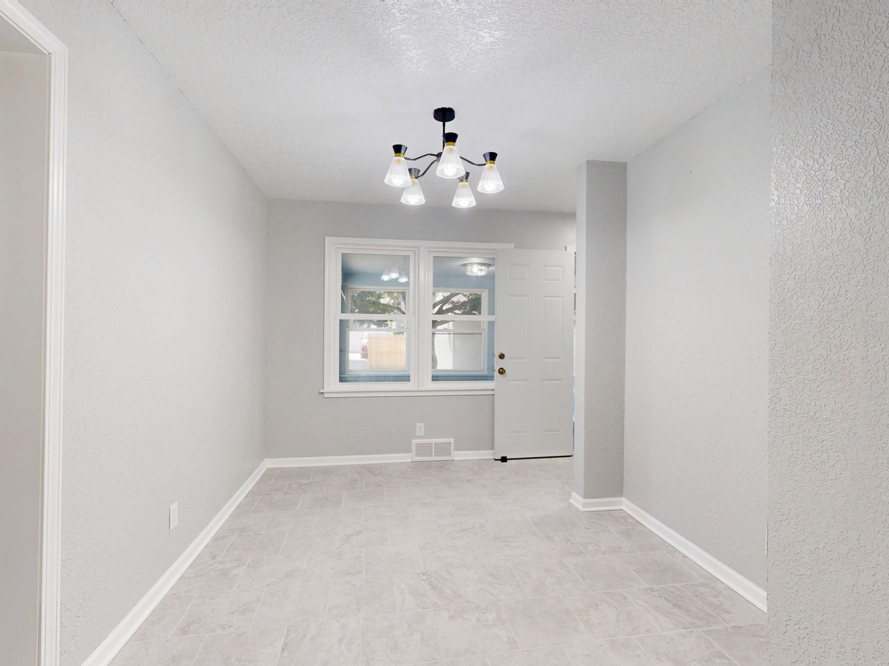 gallery-03 A spacious, empty room with a modern light fixture and large windows showcasing a minimalist design.