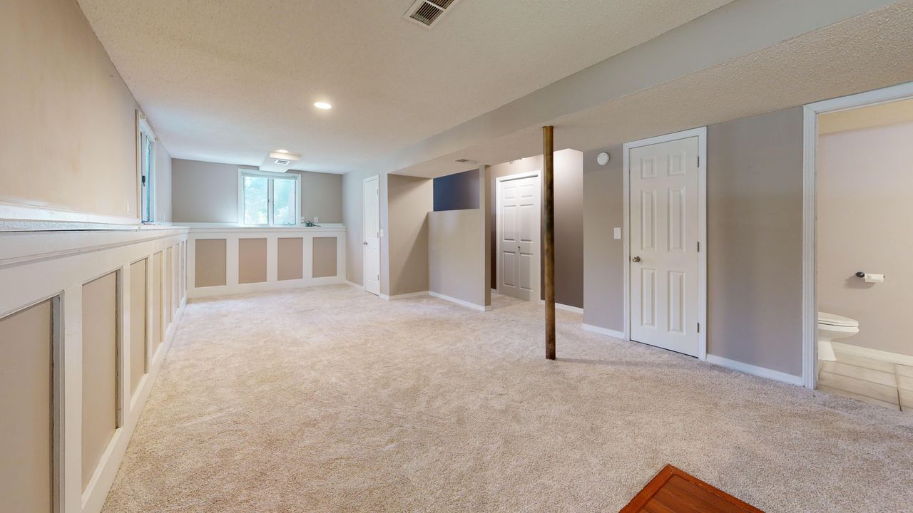 portfolio-05 Bright and clean modern basement with carpet flooring and recessed lighting.