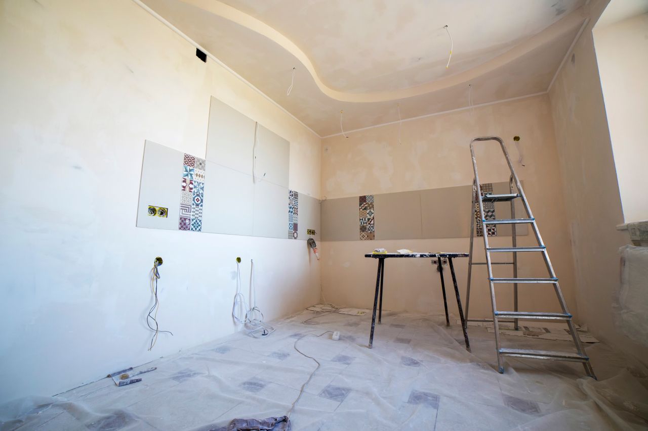 services-01 Interior view of a room under renovation with paint, tiles, and tools.